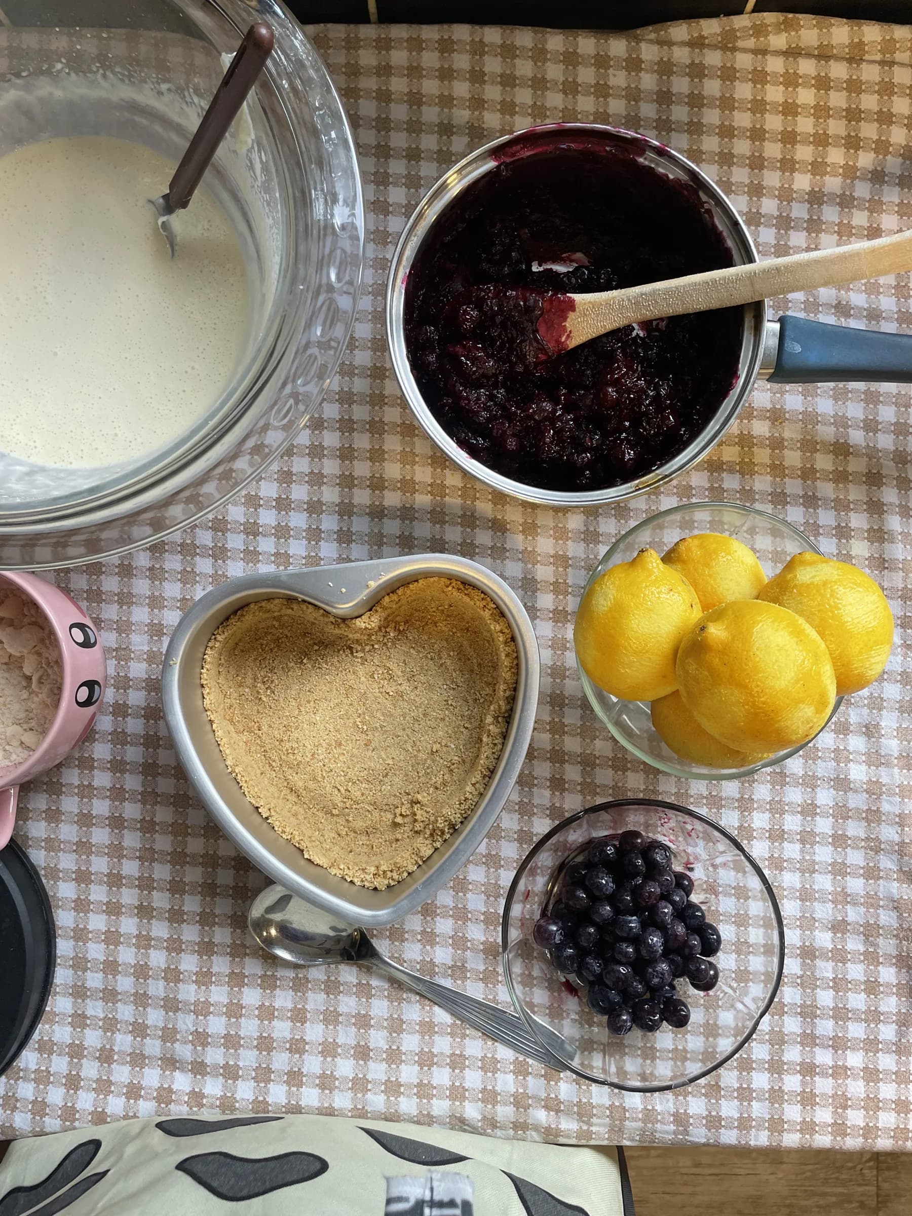 Ingredientes para preparar cheesecake sobre una mesa a cuadros